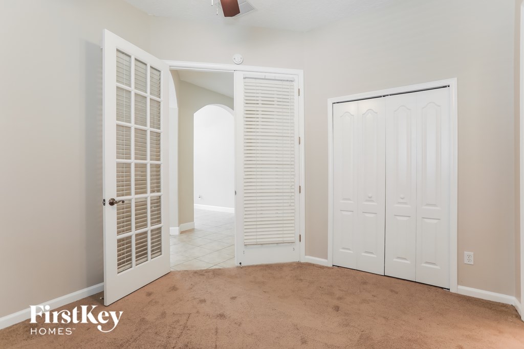 A room with a carpeted floor and a white door with a window.