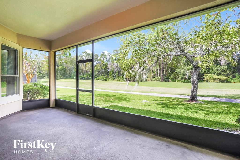 A room with a view of a tree and grass through the windows.
