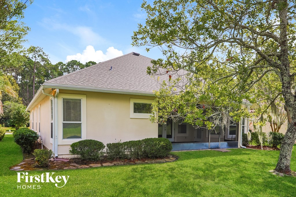 A house with a well-kept lawn and trees in front.