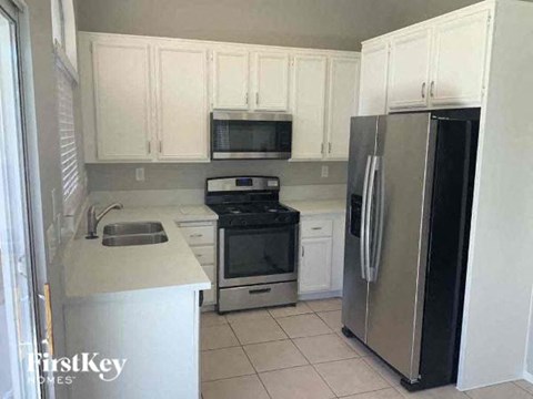A kitchen with white cabinets and a stainless steel refrigerator.