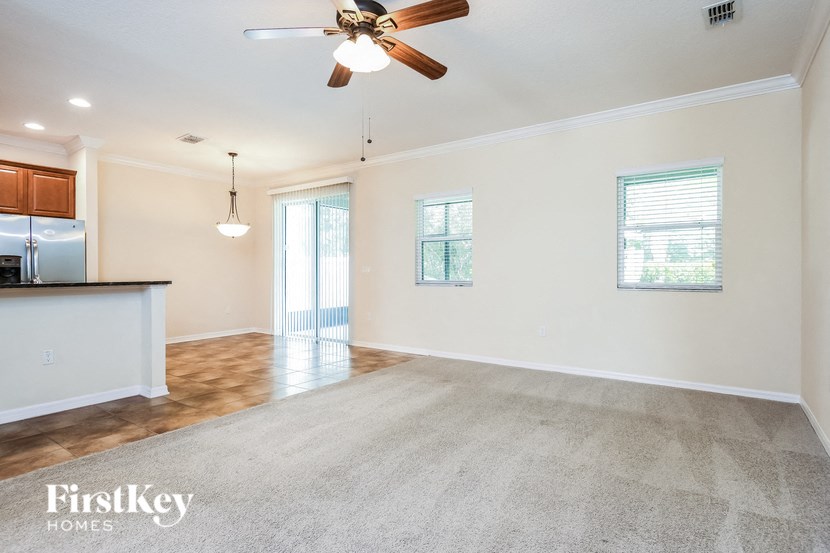 an empty living room and kitchen with a ceiling fan