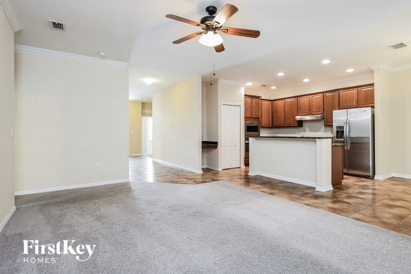 an empty living room and kitchen with a ceiling fan