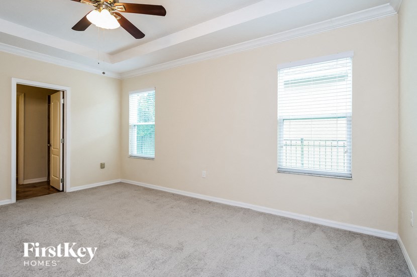 an empty living room with a ceiling fan and two windows