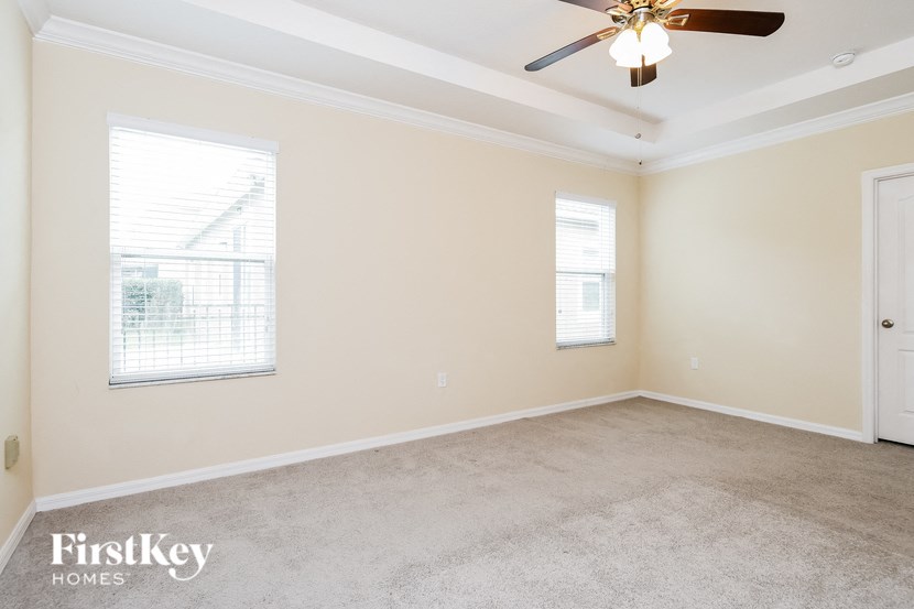 an empty room with a ceiling fan and two windows