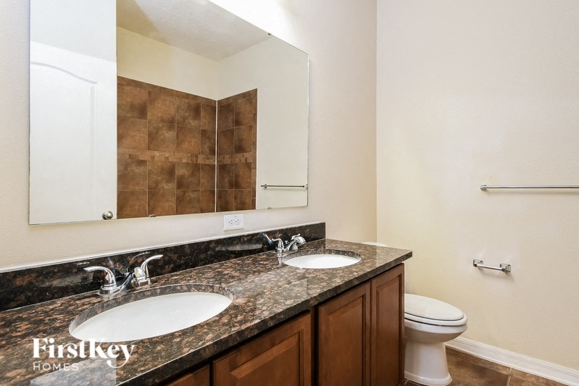 a bathroom with two sinks and a toilet and a mirror
