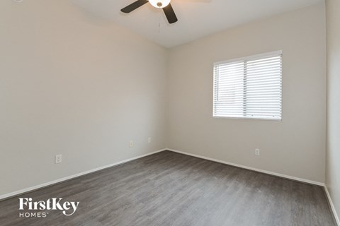 the spacious bedroom with wood flooring and a ceiling fan