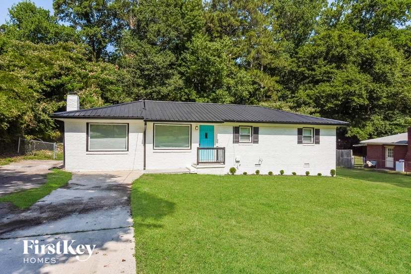 a small white house with a blue door and a green lawn