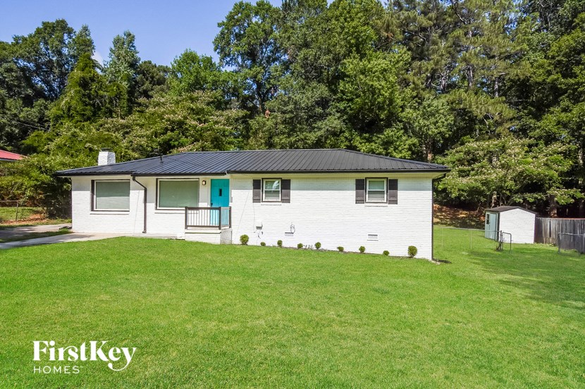 a small white house with a green yard and trees