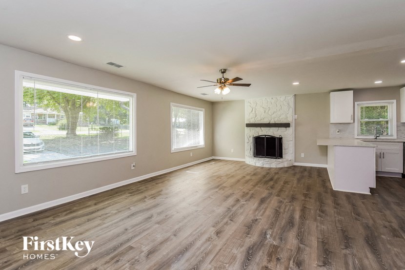 an empty living room with a fireplace and a ceiling fan