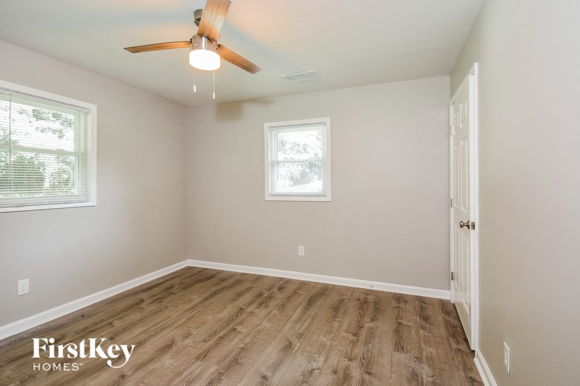 an empty bedroom with a ceiling fan and wood floors