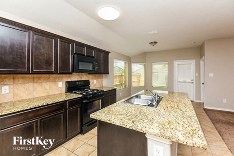 A kitchen with granite countertops and dark brown cabinets.