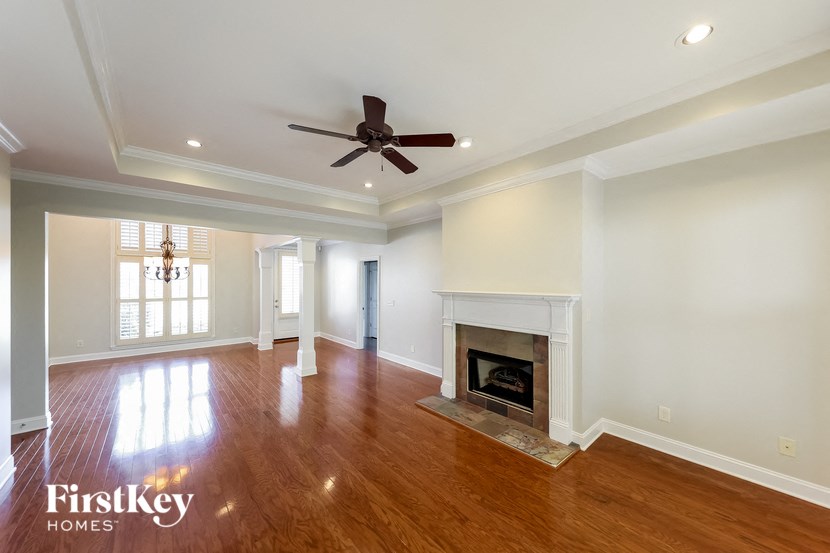 A spacious living room with a fireplace and a ceiling fan.