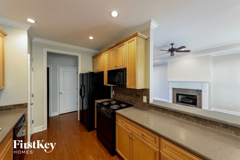 A kitchen with wooden cabinets and a black refrigerator.