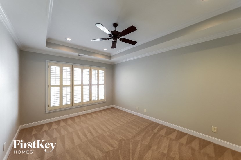 A room with a ceiling fan and a window with blinds.