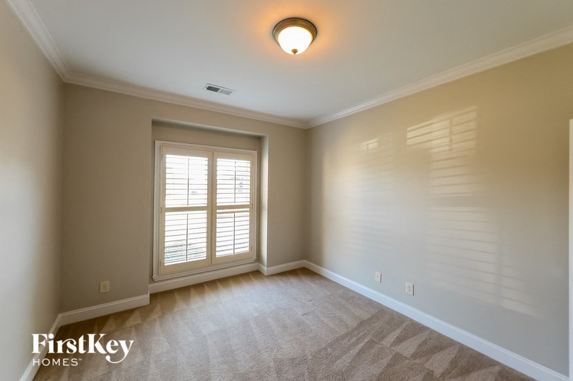 A room with a window and a carpeted floor.