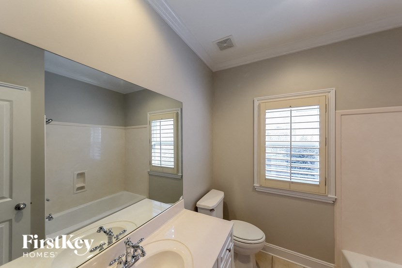 A bathroom with a toilet, sink, and mirror.
