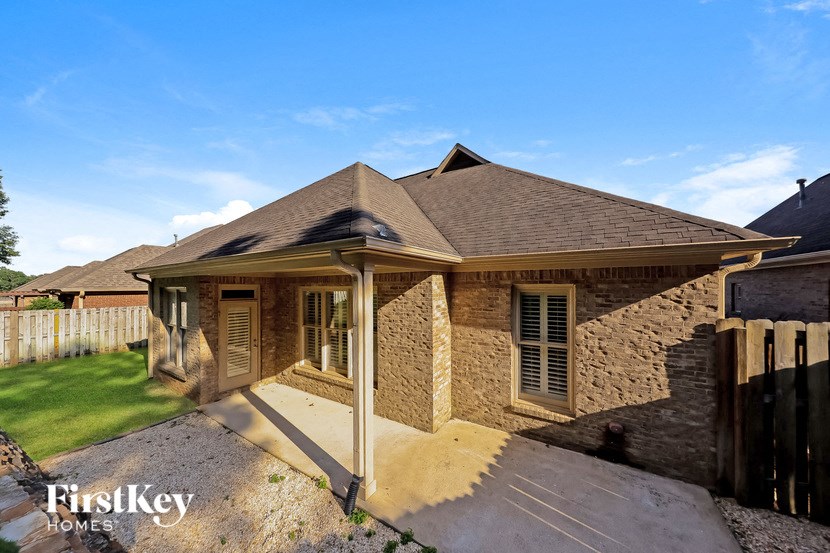 A house with a brown roof and a stone wall is shown.