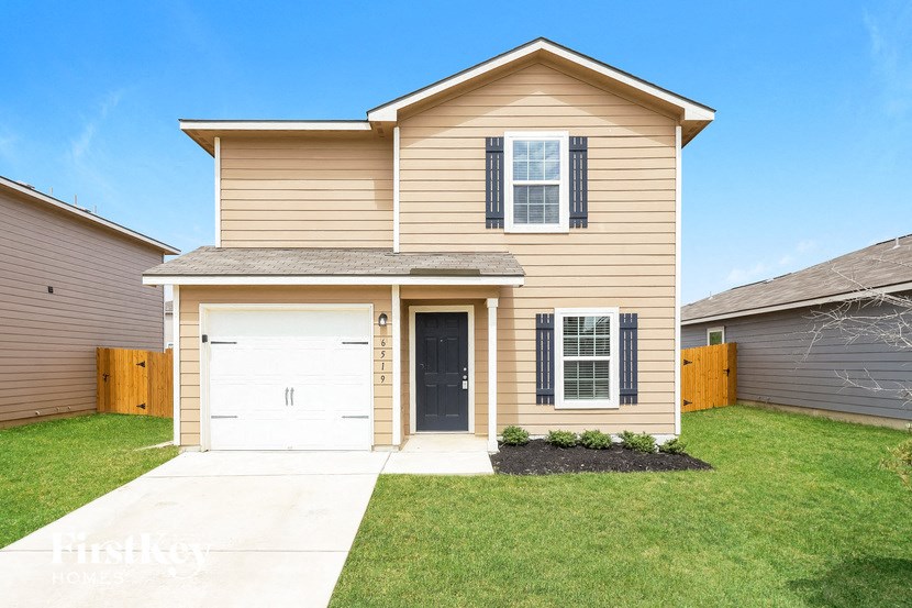 a tan house with a white garage door and a lawn