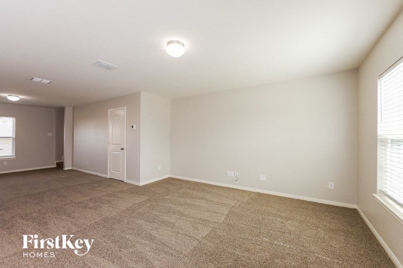 a spacious living room with a carpeted floor and a window