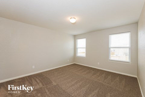 the living room of a home with carpet and two windows