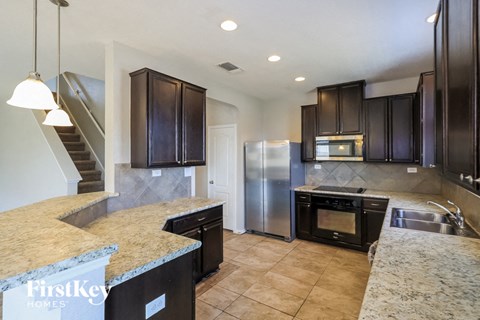 a kitchen with granite counter tops and a stainless steel refrigerator