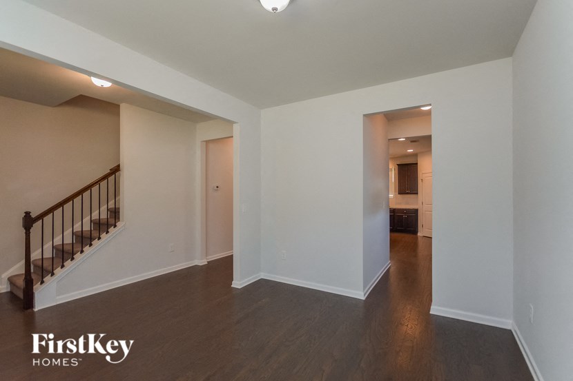 a renovated living room with a staircase and a hallway to a bedroom and bathroom