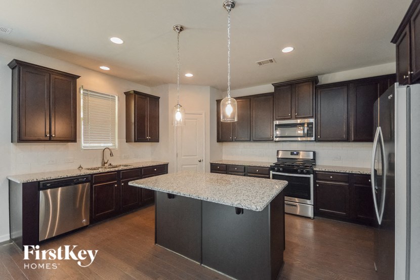 a kitchen with dark wood cabinets and granite counter tops and stainless steel appliances