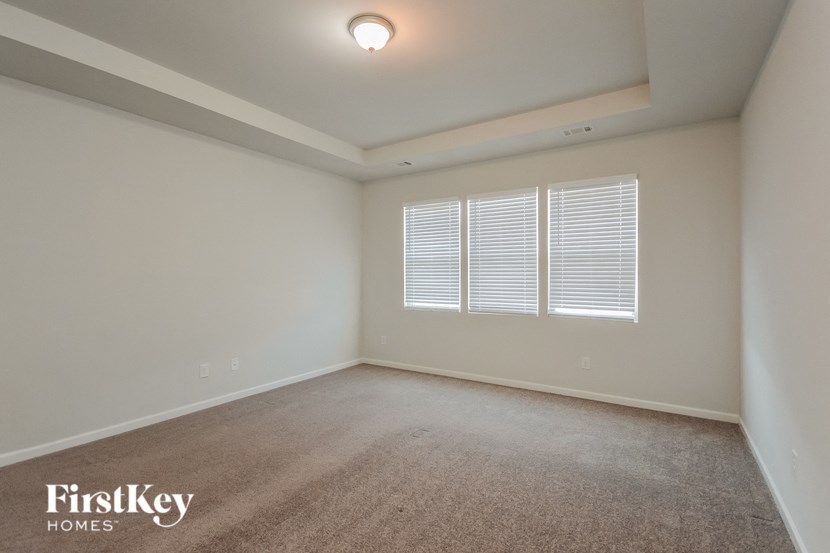 a spacious living room with two windows and a carpeted floor