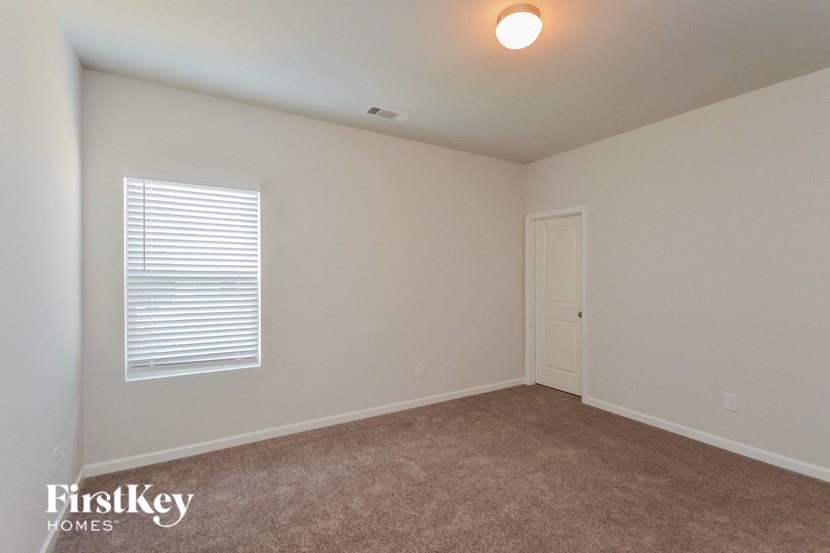 a bedroom with a carpeted floor and a window and a door