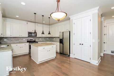 A kitchen with white cabinets and a wooden island.