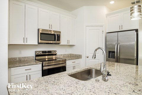 a white kitchen with granite counter tops and stainless steel appliances