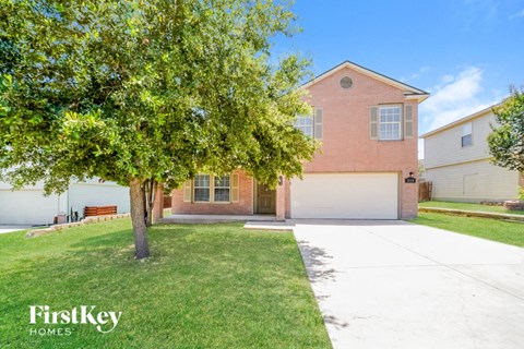 a house with a driveway and a tree in front of it