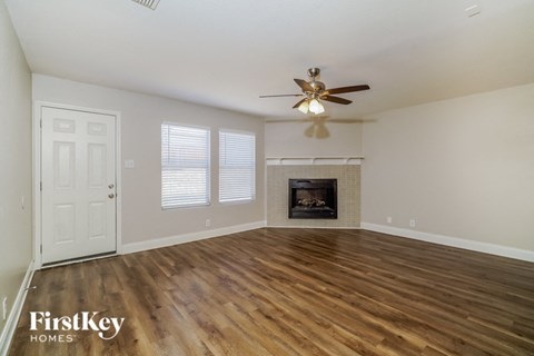 an empty living room with a ceiling fan and a fireplace