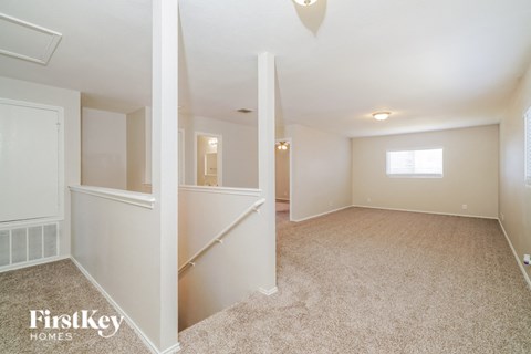 a renovated living room with a carpeted floor and a staircase
