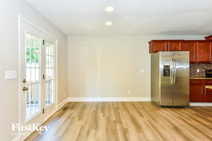 an empty kitchen with wood flooring and a stainless steel refrigerator