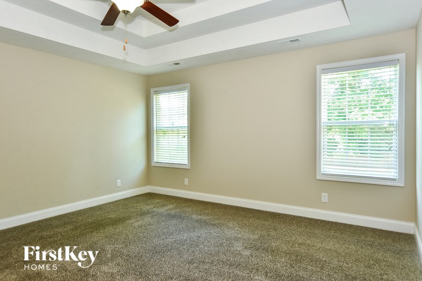 a empty room with a ceiling fan and two windows