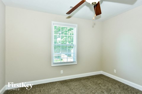 a bedroom with a window and a ceiling fan
