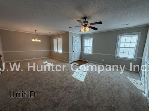 A spacious room with a ceiling fan and carpeted floor.