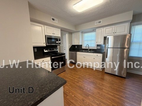 A kitchen with white cabinets and a black countertop.