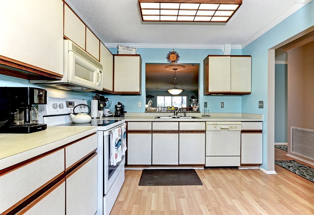 a kitchen with white cabinets and appliances and a wood floor