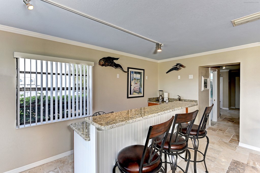 a bar with four stools in a living room with a door to a kitchen