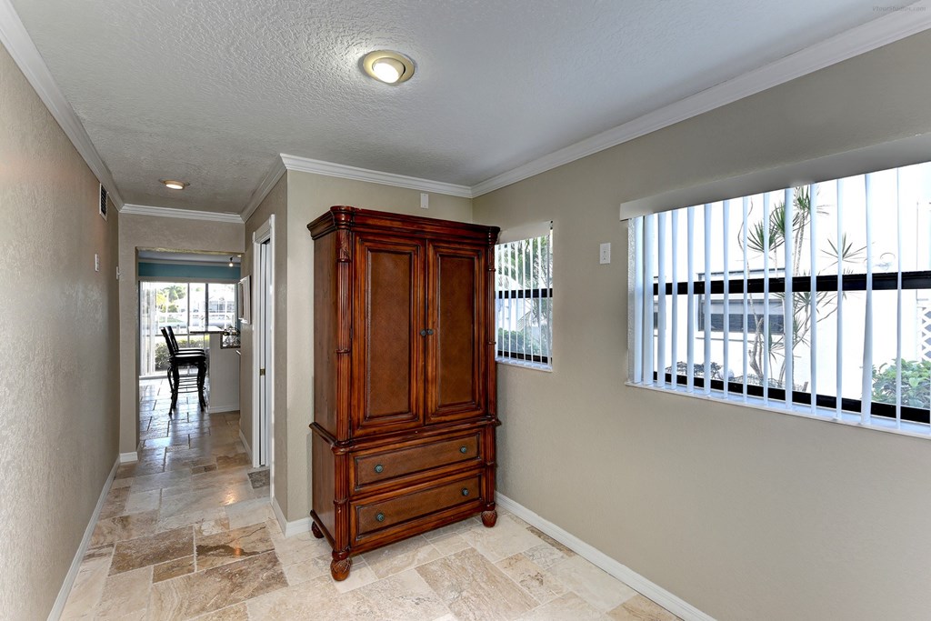 an entryway with a wooden armoire and a large window with a balcony