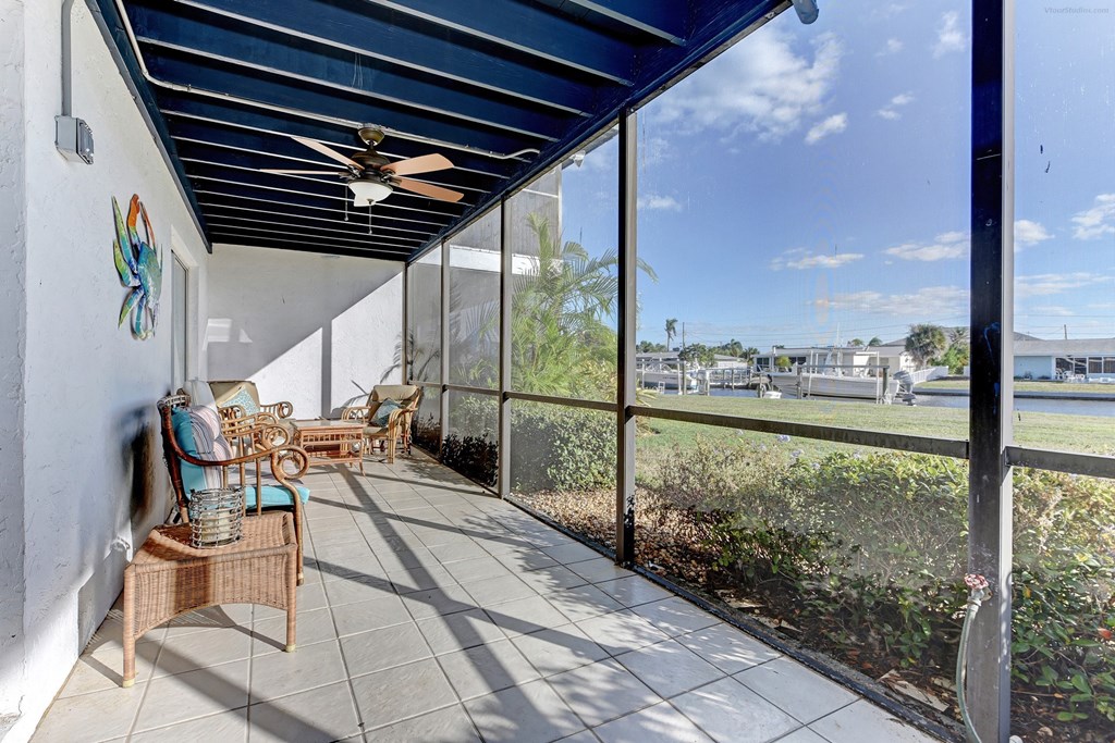 a covered porch with a ceiling fan and glass windows