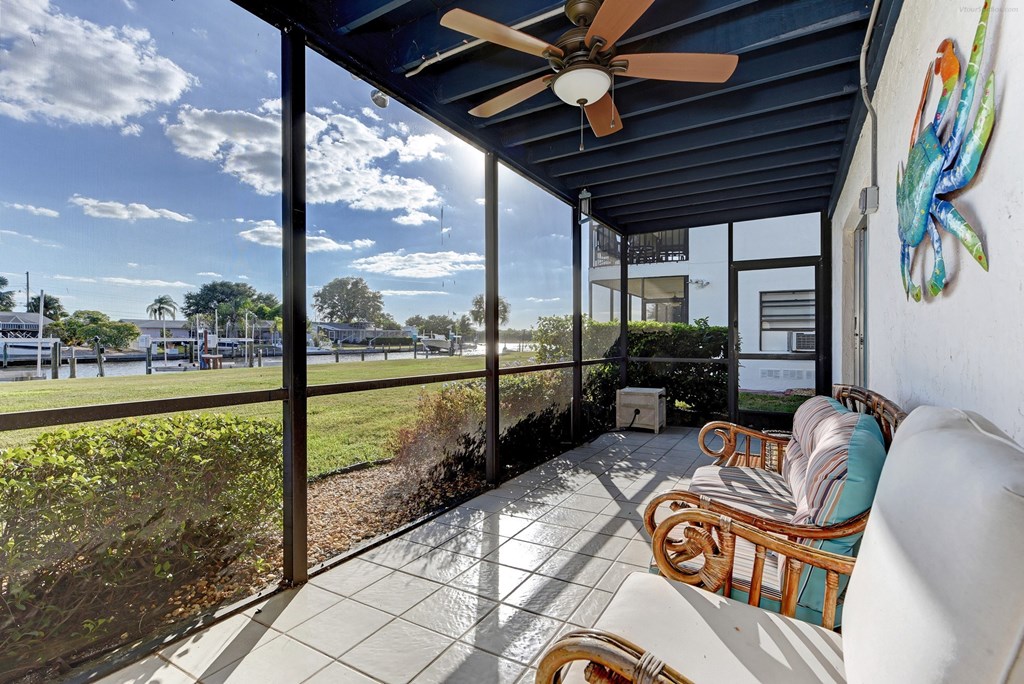 a covered porch with a ceiling fan and chairs