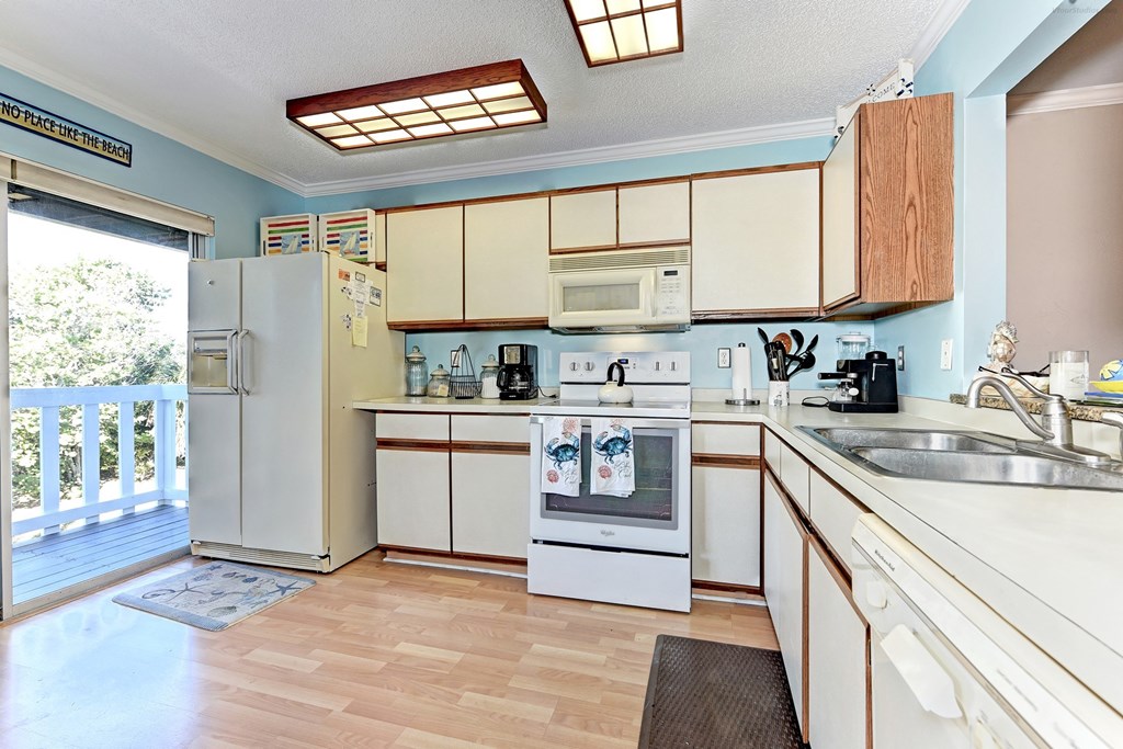 a kitchen with white cabinets and appliances and a door to a balcony