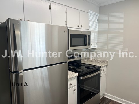 A kitchen with a stainless steel refrigerator and a black stove top oven.