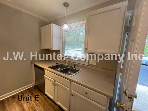 A kitchen with white cabinets and a sink is shown with the text "J.W. Hunter Company Inc." and "Unit E" on the image.