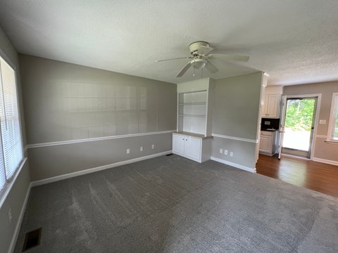 A spacious room with a ceiling fan and a window with blinds.