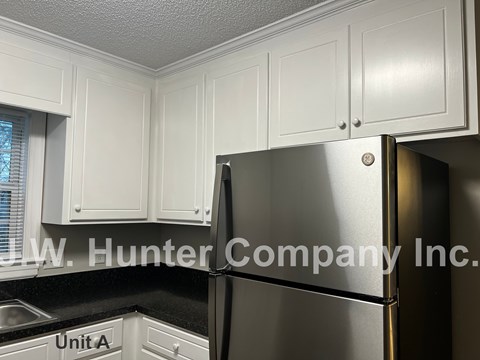A stainless steel refrigerator in a kitchen with white cabinets.