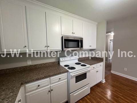 A kitchen with white cabinets and a granite countertop.